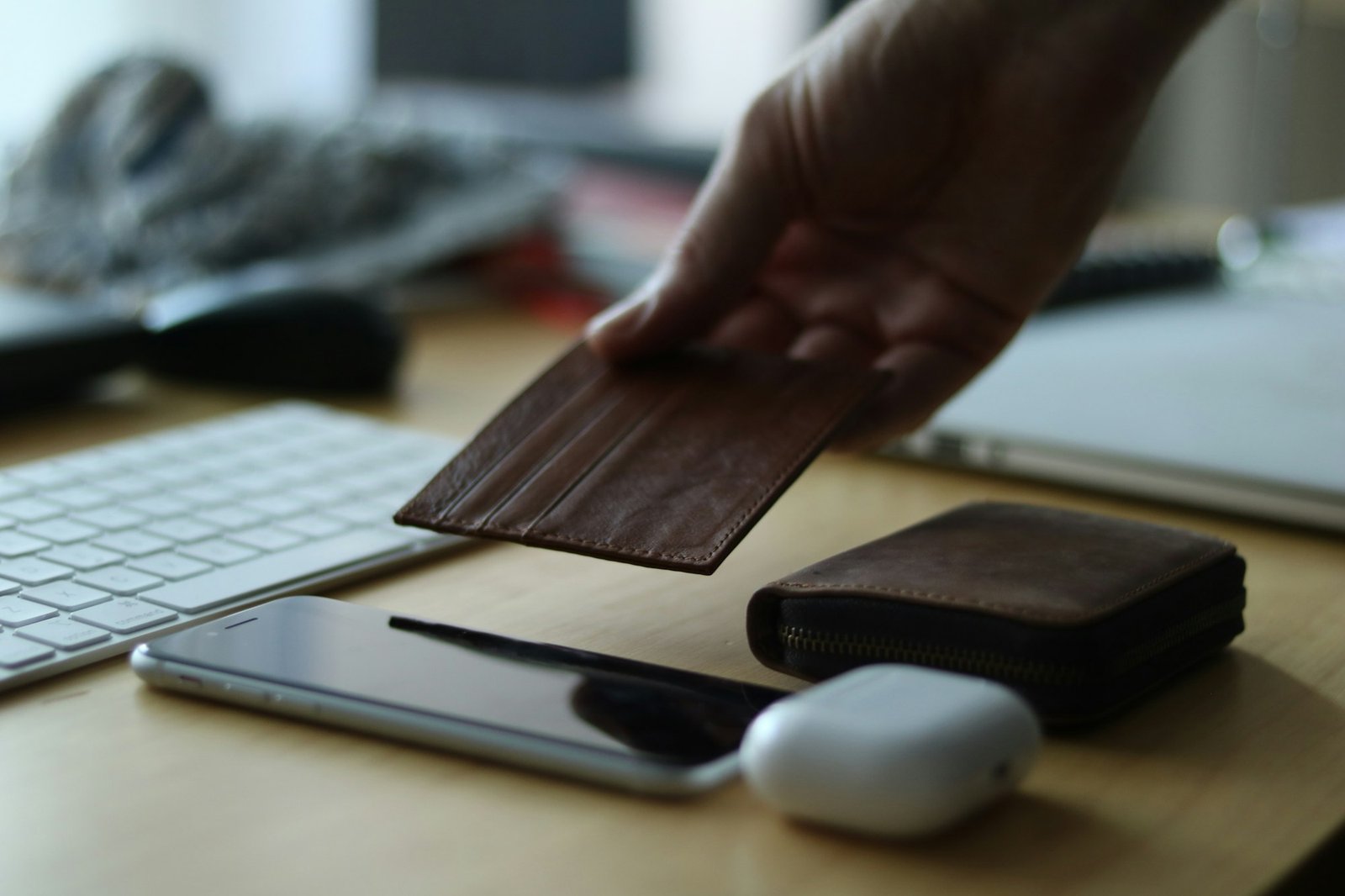 A person holding a smartphone with a wallet next to a keyboard